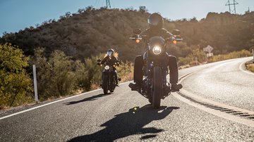 Two bikers ride on road
