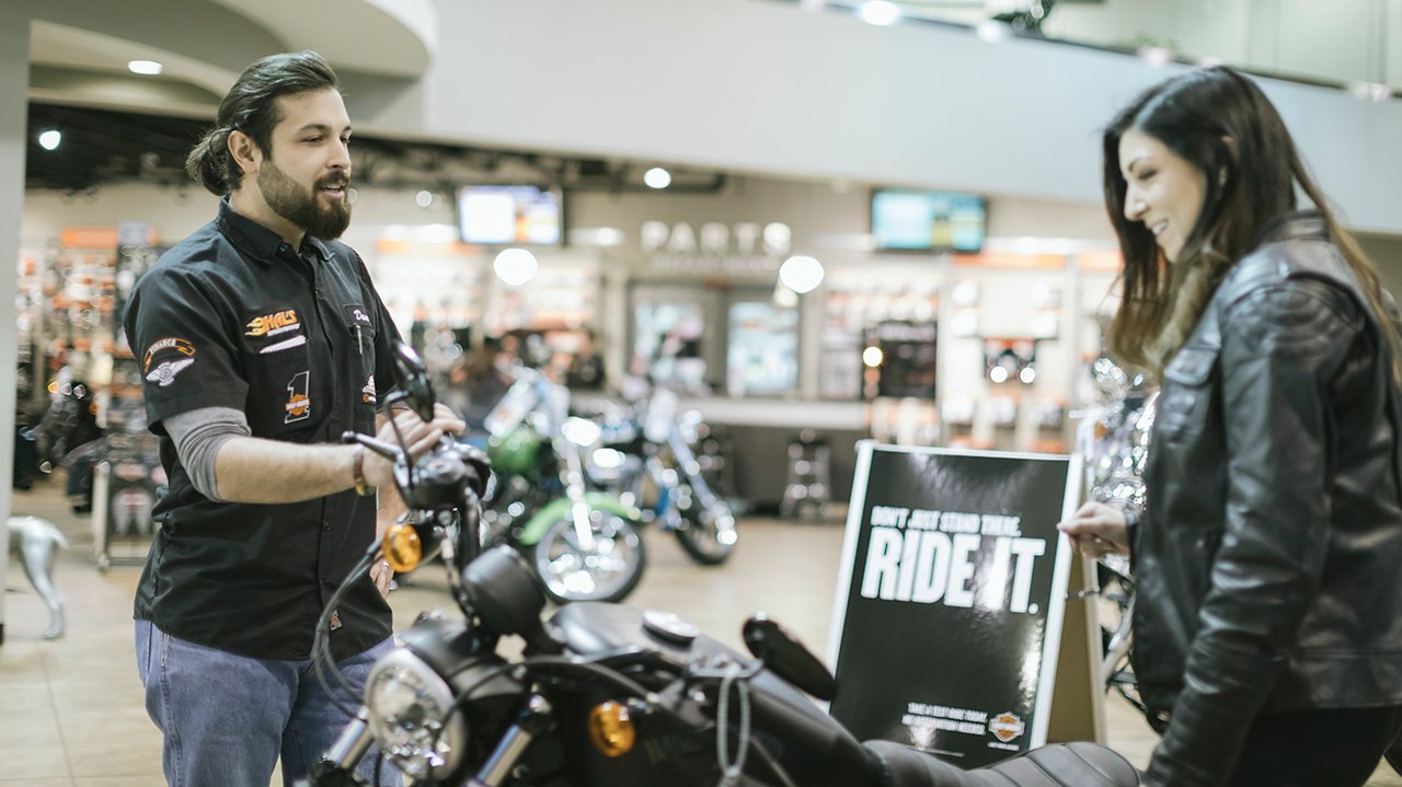 forhandlers medarbejder, der hjælper en kunde med at købe motorcykel
