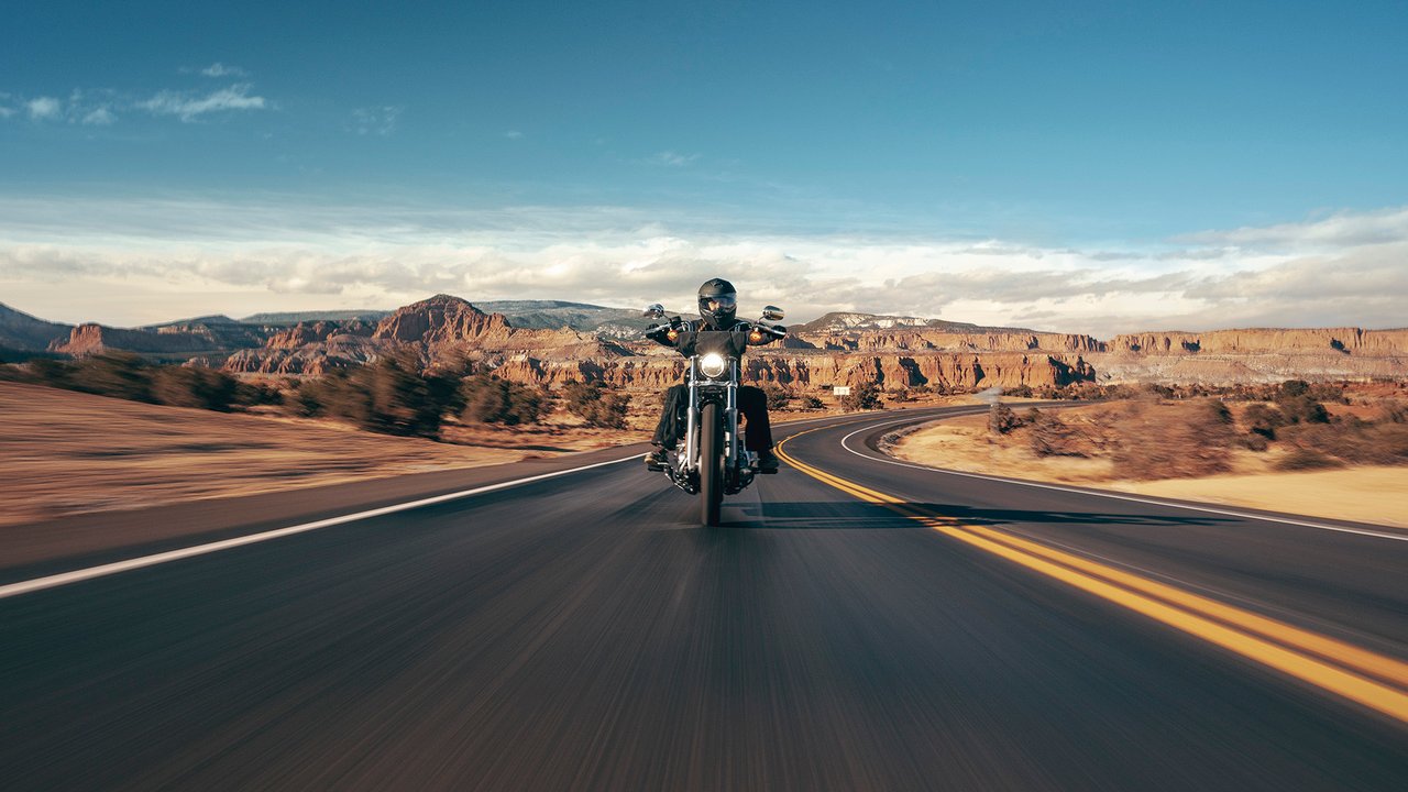 Motocicleta Cruiser sendo pilotada em uma estrada rural