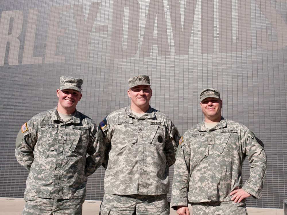 Three military personnel standing in front of the H-D Museum