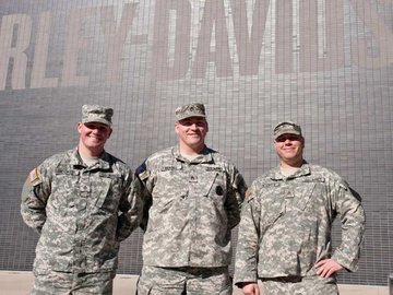 Three military personnel standing in front of the H-D Museum