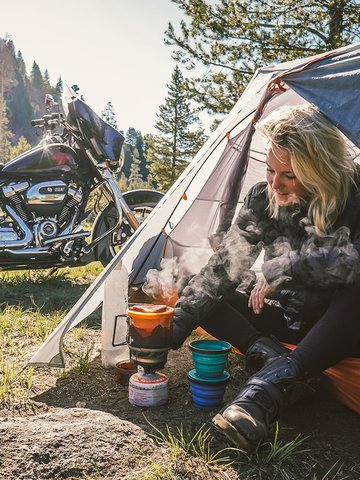 Woman sitting in a tent with a motorcycle in the background