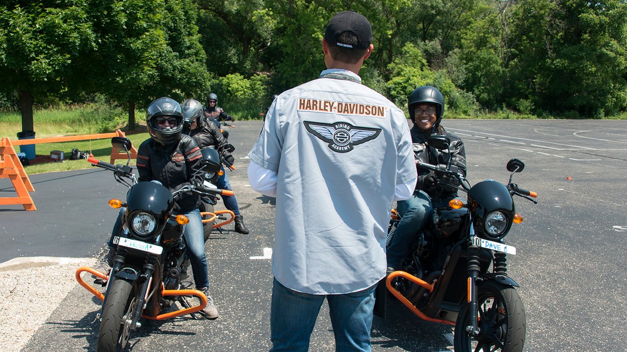 Pessoas aprendendo a pilotar uma motocicleta em um campo de treinamento