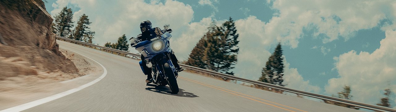 Motorcyclist on a blue bike rides a winding mountain road