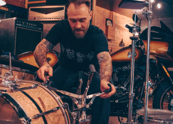Man wearing Harley-Davidson shirt sets up drum set