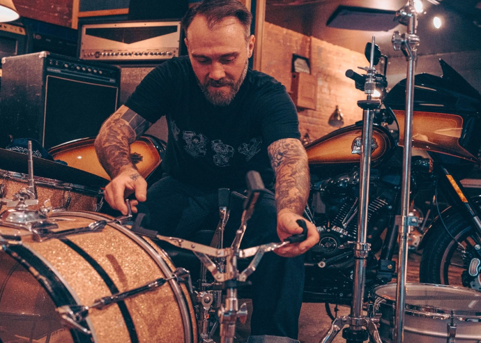 Man wearing Harley-Davidson shirt sets up drum set