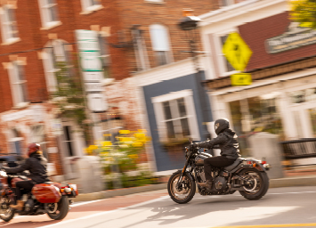 Two motorcyclists ride their bikes through town