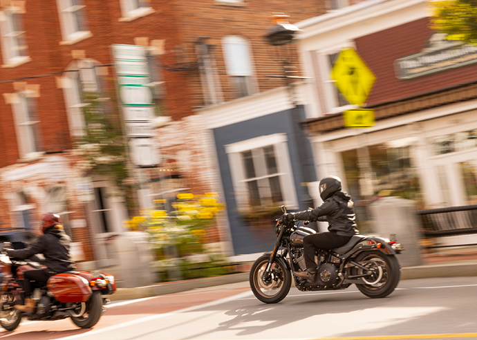 Two motorcyclists ride their bikes through town