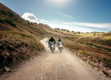 Two motorcycle riders riding on dirt trail