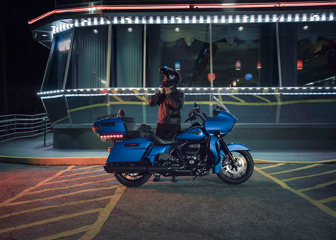 Larry Ware Jr stands next to his Road Glide Limited bike parked outside of a restaurant