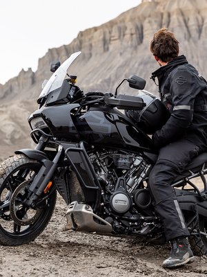 Mustiin Harley-asusteisiin sonnustautunut kuski Harley-Davidson Pan America Adventure Touring -moottoripyörän kanssa