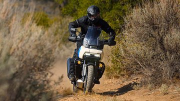 骑手驾驶开着车头灯的Pan America 1250定制版摩托车穿越沙漠