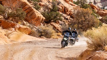 Çöl arazisinde Pan America 1250 motosikletleriyle ilerleyen iki sürücü