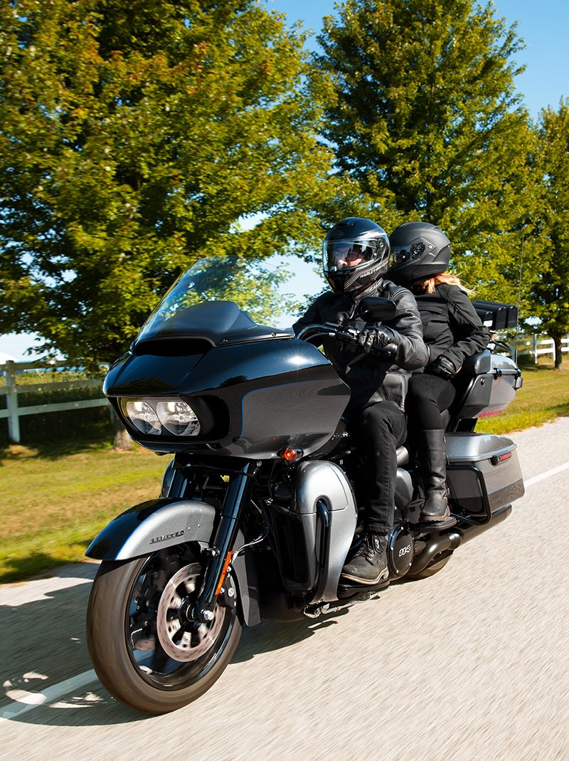 Jezdec v černém oblečení Harley jedoucí na motocyklu Road Glide Limited 2022 v barvě Billiard Red