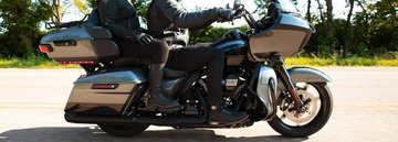 Jezdec v černém oblečení Harley jedoucí na horské silnici na motocyklu Road Glide Limited 2022 v barvě Billiard Red.