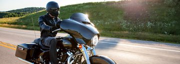 Conducteur en tenue Harley noire conduisant une Street Glide 2022 dévalant une route de montagne