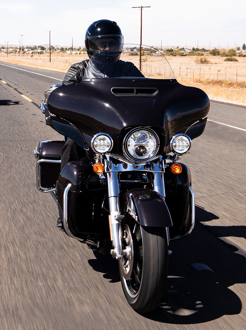 騎士以森林為背景，騎乘 2022 Harley-Davidson Ultra Limited 重車沿著公路飛馳