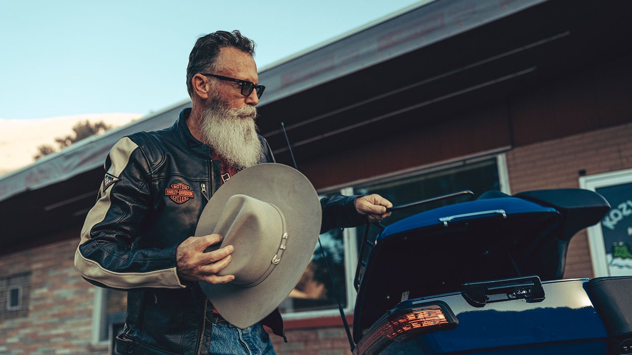 Man putting cowbay hat in Road Glide Limited luggage carrier