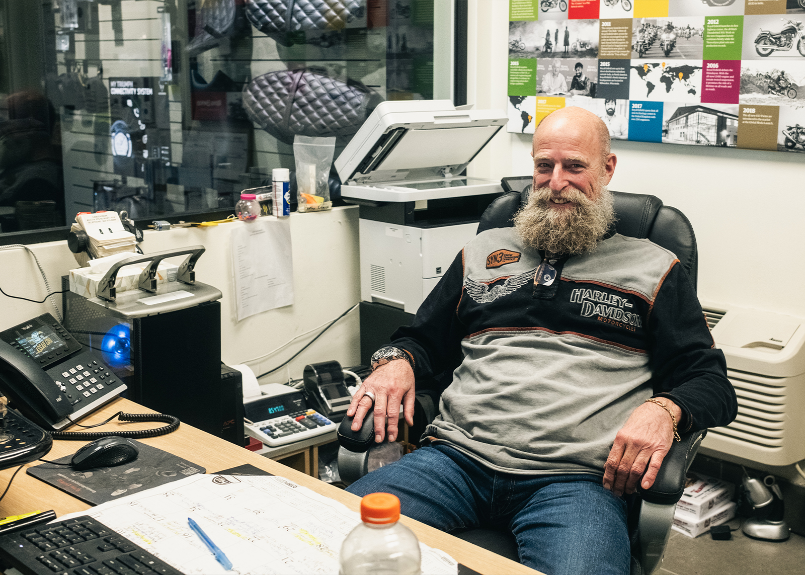 An employee with a big beard sits behind a desk in his office at Harley-Davidson of Nassau County.