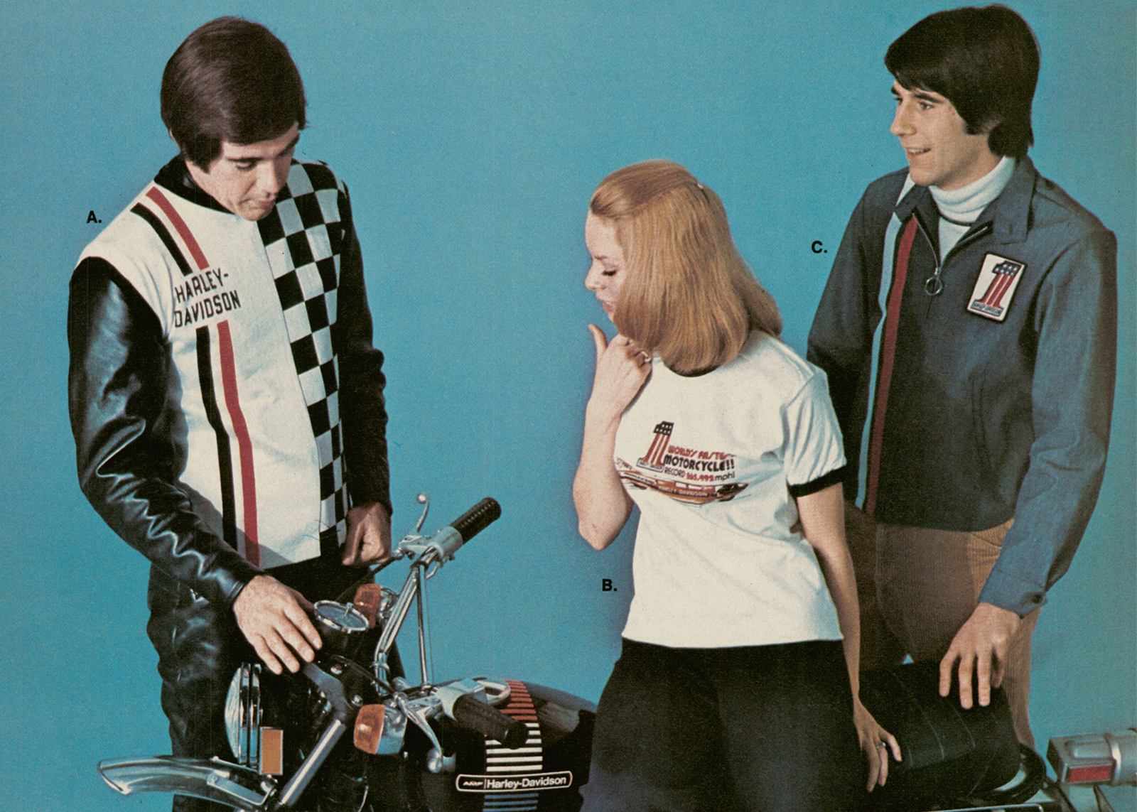 Three people stand around a motorcycle in a studio wearing H-D clothing