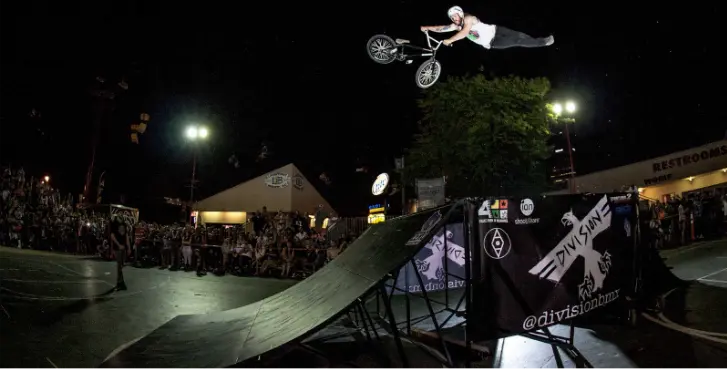 夜のイベントでランプの上空でアクロバティックな技を披露するBMXライダー