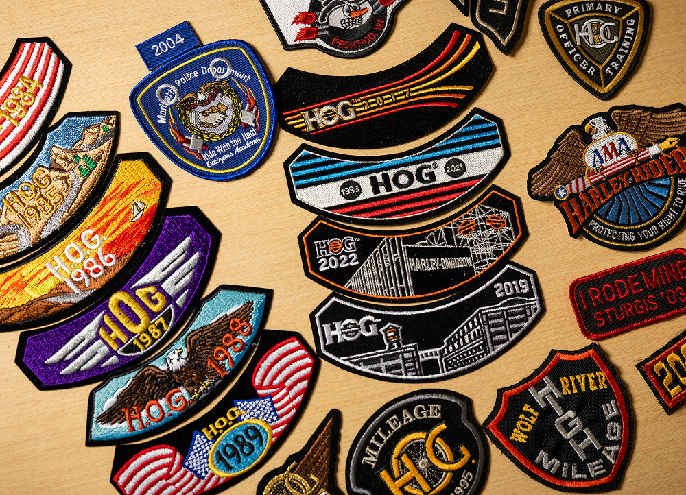 Collection of embroidered motorcycle club patches arranged on a surface, featuring bold colors and designs