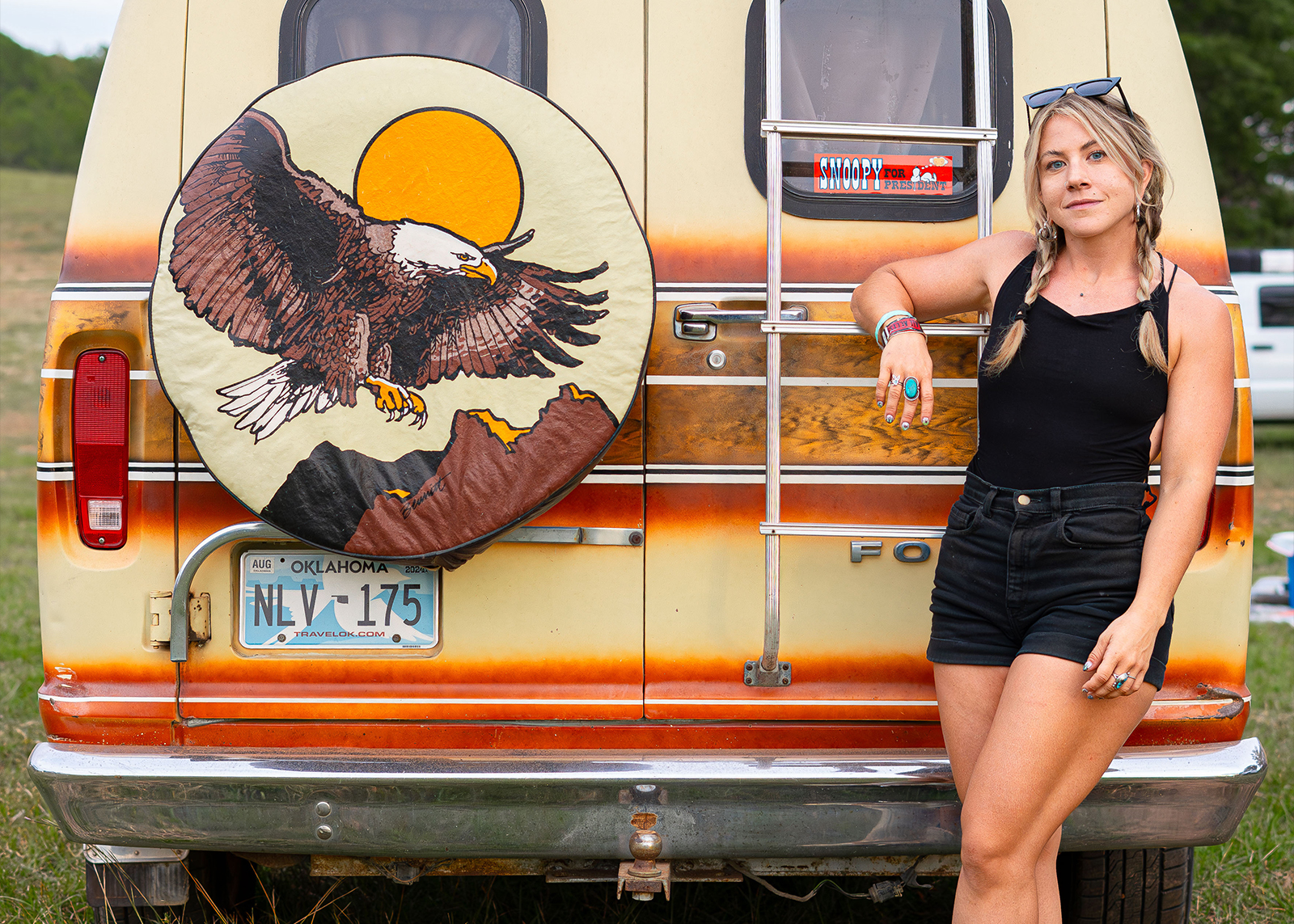 A woman poses with a van with a bald eagle spare tire cover