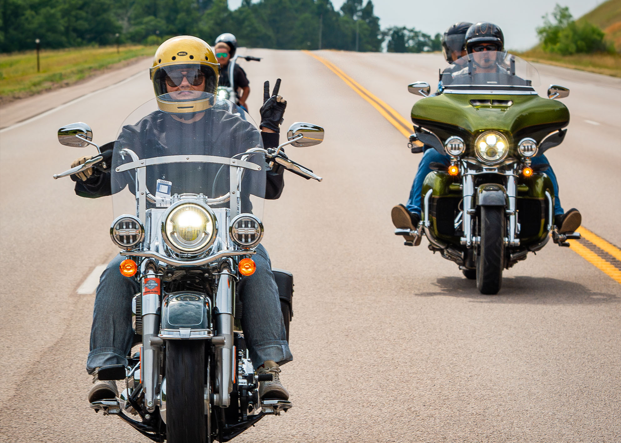 A really cute girl on a motorcycle holds up a peace sign 