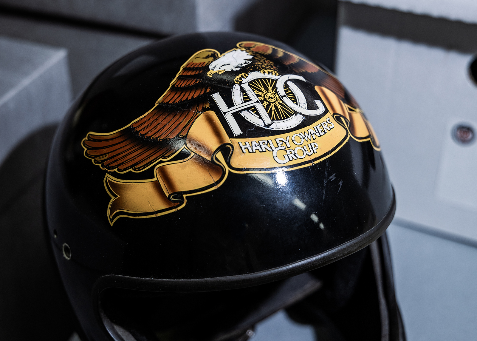 A vintage black plastic motorcycle helmet with a large H.O.G. Harley Owners Group eagle and banner logo sticker on top.