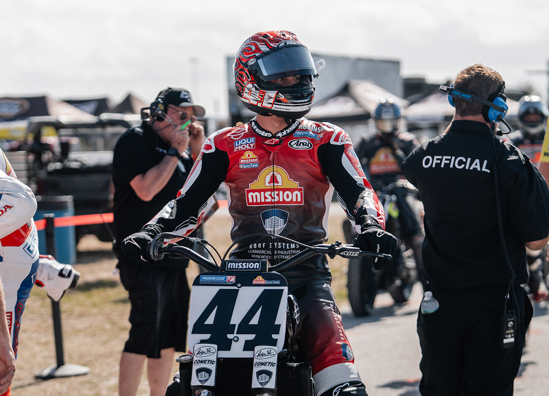 Brandon Robinson aboard bike #44 waits in the paddock before a flat track race, surrounded by crew and officials