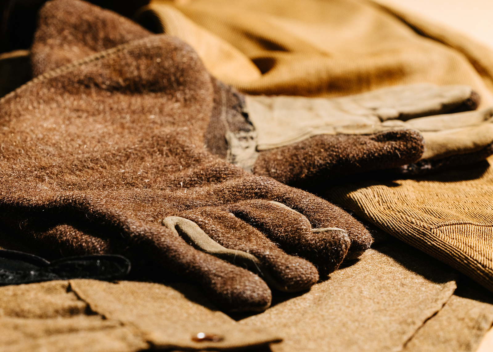 A collection of vintage motorcycle gear including leather helmets, goggles, boots, and wool clothing.