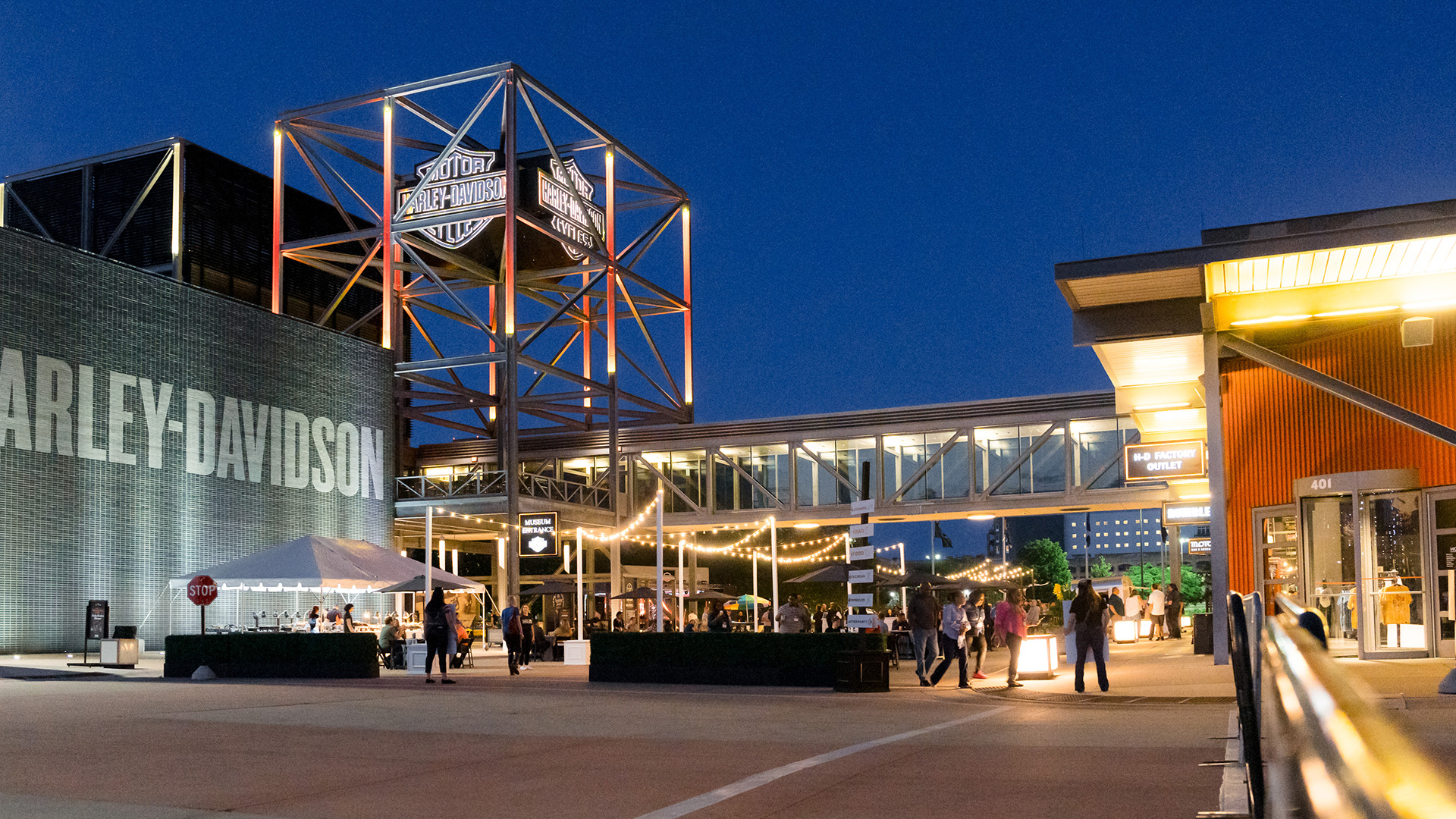 Harley-Davidson campus courtyard with people and lit tower at night