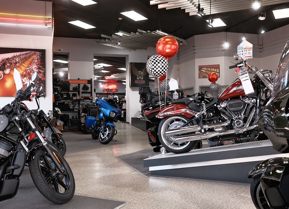 Precision H-D showroom floor with motorcycles on display platform, balloons overhead and accessories in background