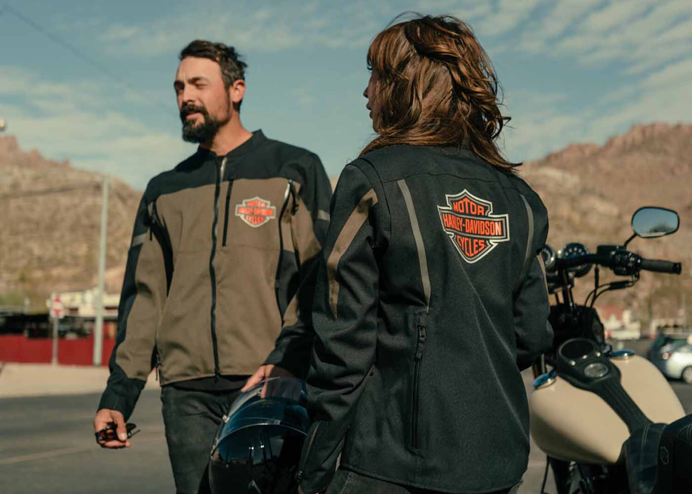 Man & woman wearing H-D jackets by motorcycle