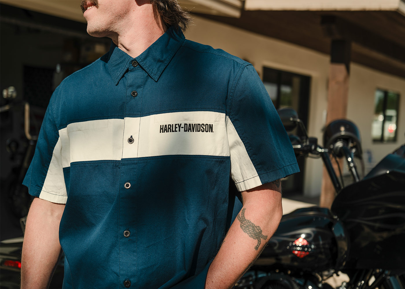 man in blue with cream stripe H-D button-up shirt near motorcycle