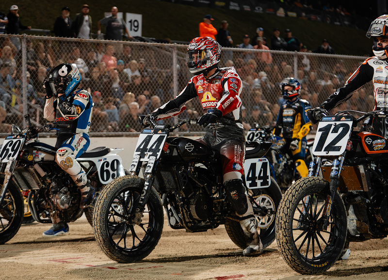 Brandon Robinson sits on motorcycle #44 on the starting grid before a flat track race, surrounded by competitors