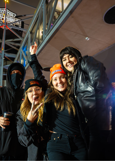Group of people posing together in front of a lit steel structure during an outdoor night event