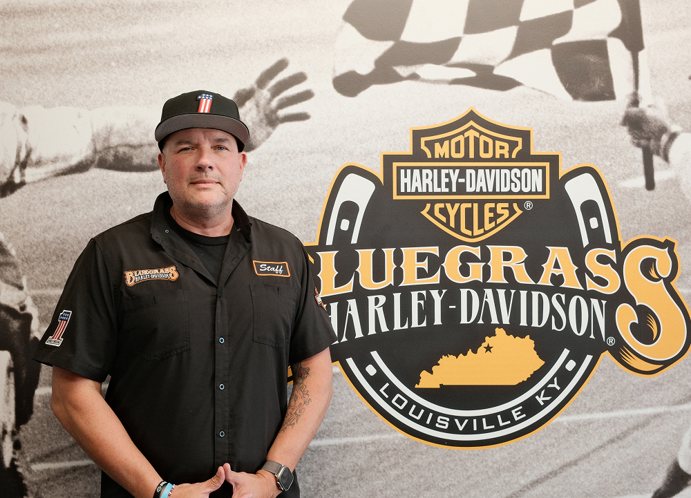 Bluegrass Harley-Davidson General Manager Jason Motz stands in front of a wall mural with the dealership logo