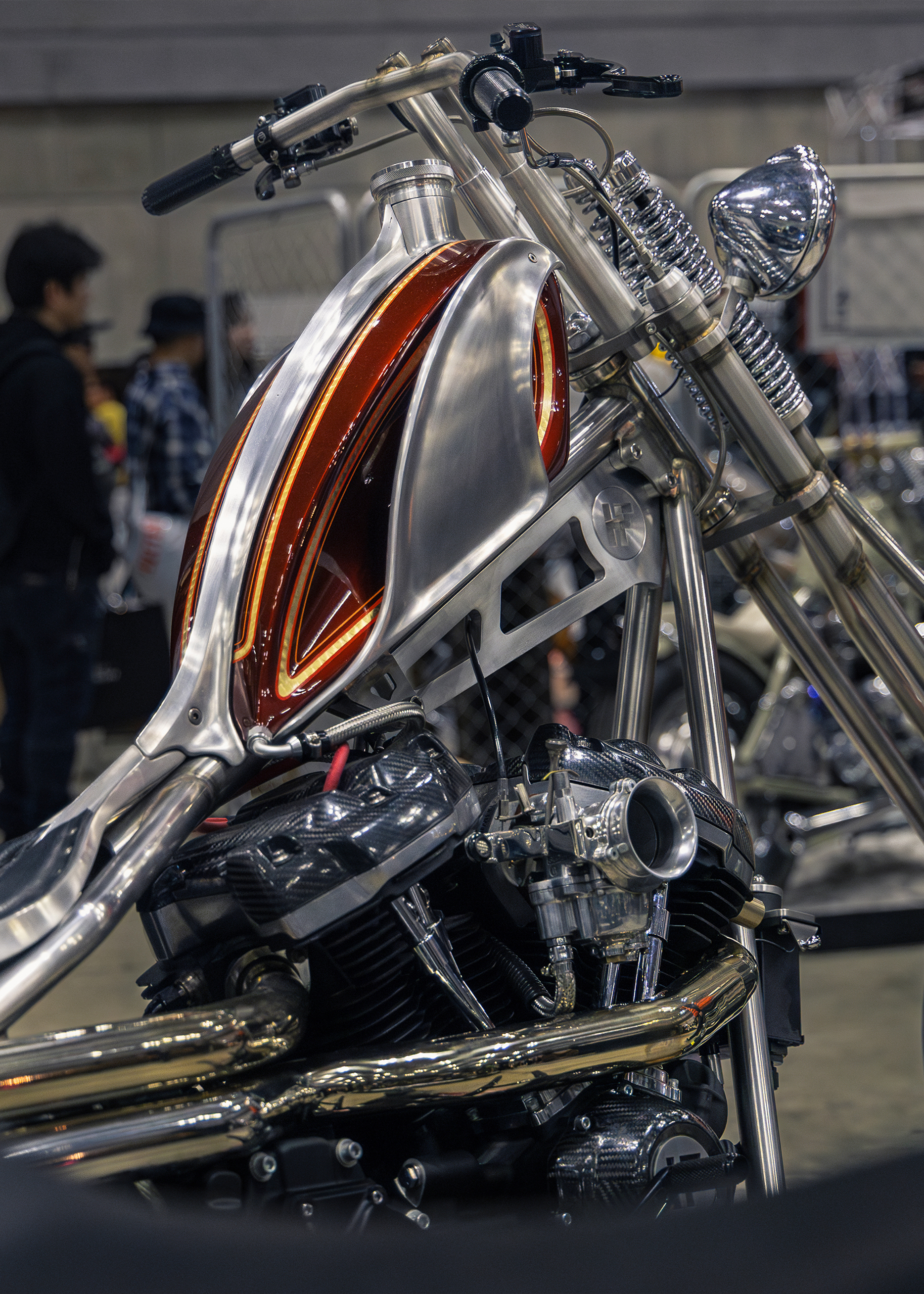 A custom motorcycle with a polished metal frame, exposed engine, and a sleek fuel tank featuring red accents