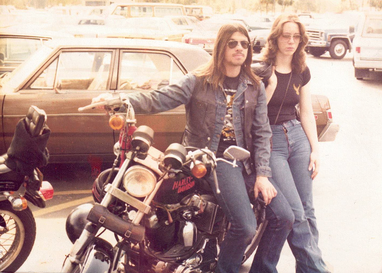 Photo from 1979 of Phil and Liz DiGennaro standing beside a Harley-Davidson motorcycle in a parking lot.