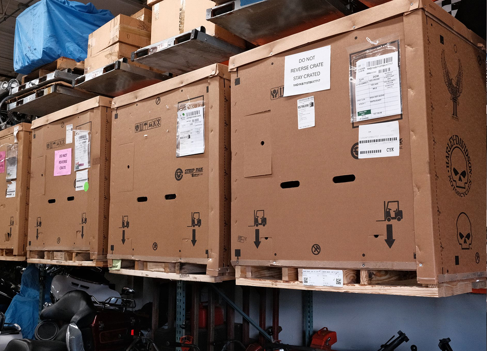 Large shipping crates stacked on warehouse racks with labels and inventory markings visible