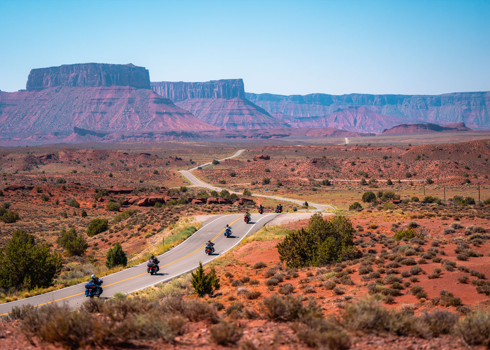A long line of bikes rides toward buttes.
