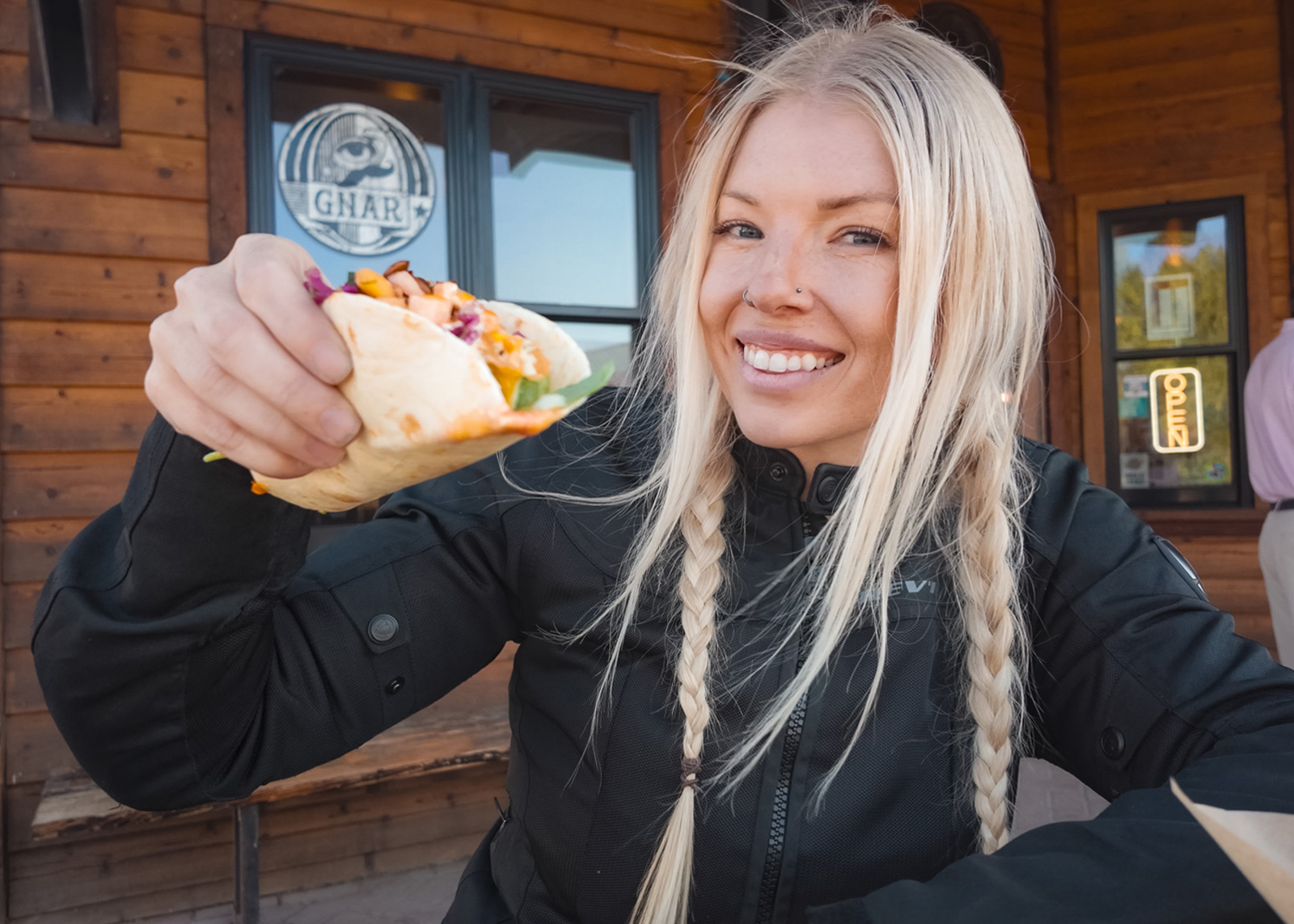 A woman smiles holding a taco