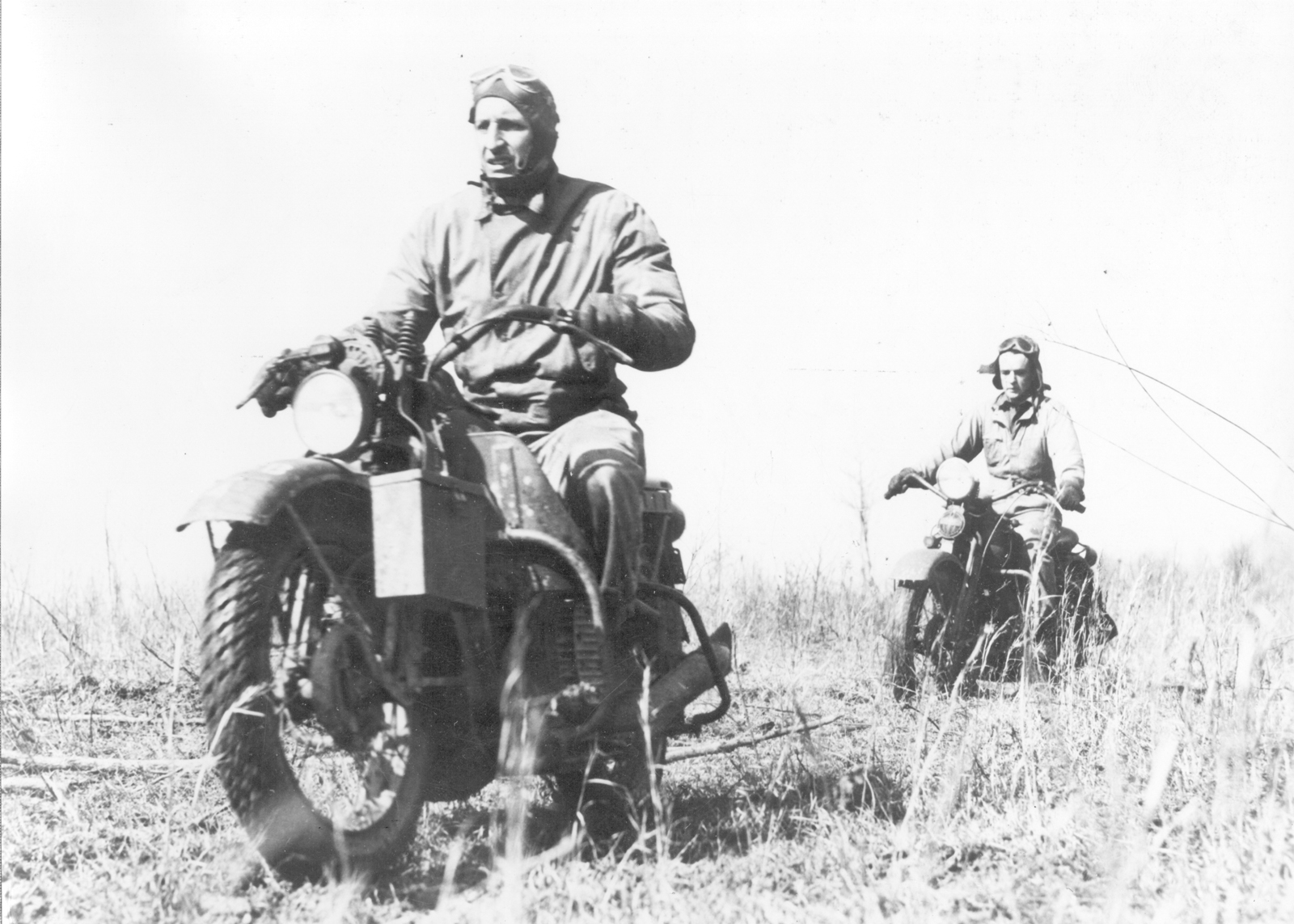 Two soldiers ride their Harley-Davidsons in an open field