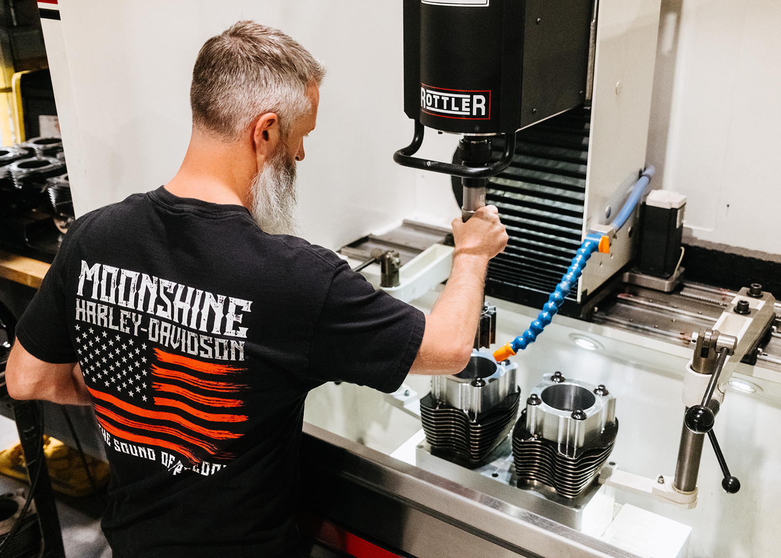 Moonshine Harley-Davidson Owner and General manager Jamie Lima guides a boring tool into the cylinder bore of a Harley-Davidson V-twin engine cylinder.