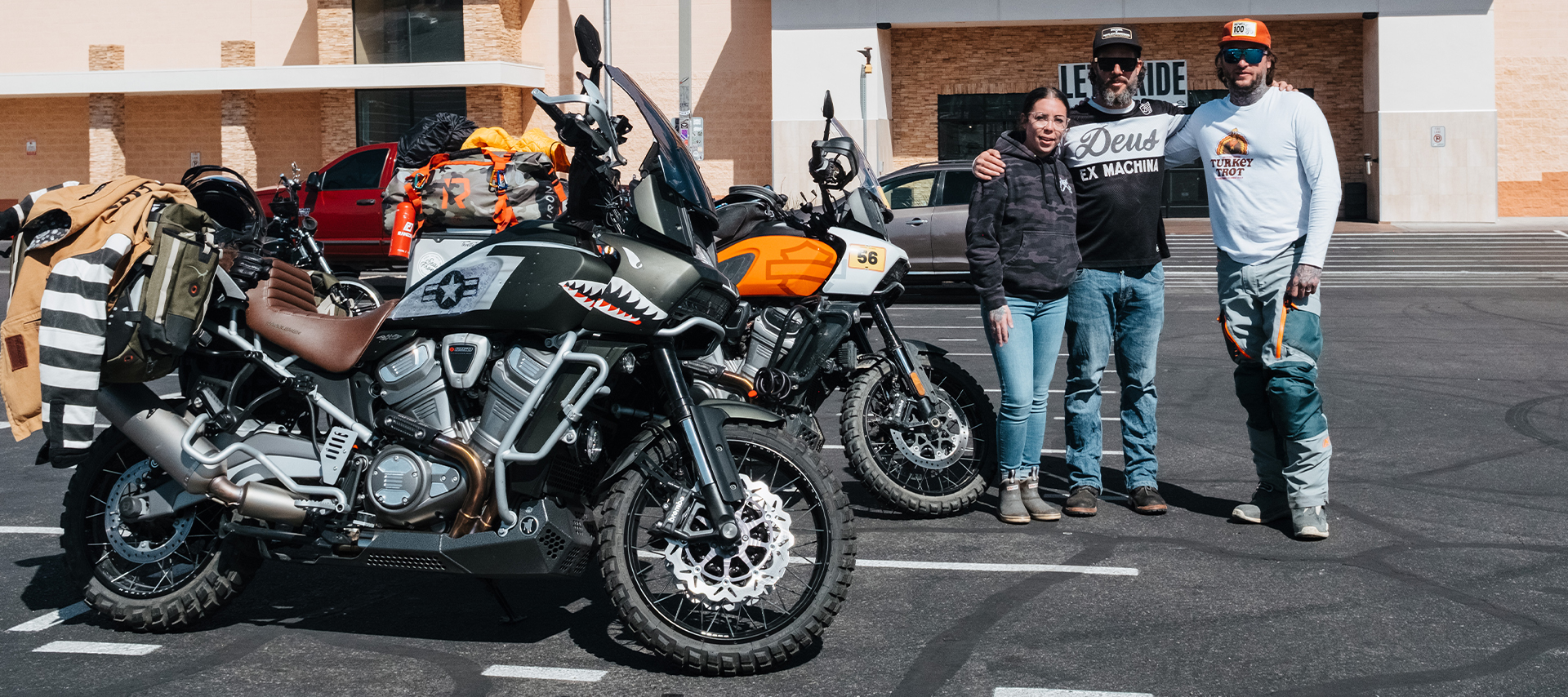 Three staff members pose next to two off-road adventure motorcycles in the parking lot of Red Rock Harley-Davidson.