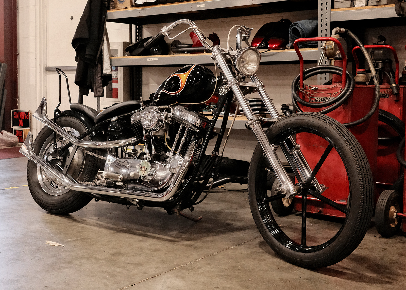 Custom Harley-Davidson chopper with black tank, flame design, and chrome details parked in the Classic Harley-Davidson service area.