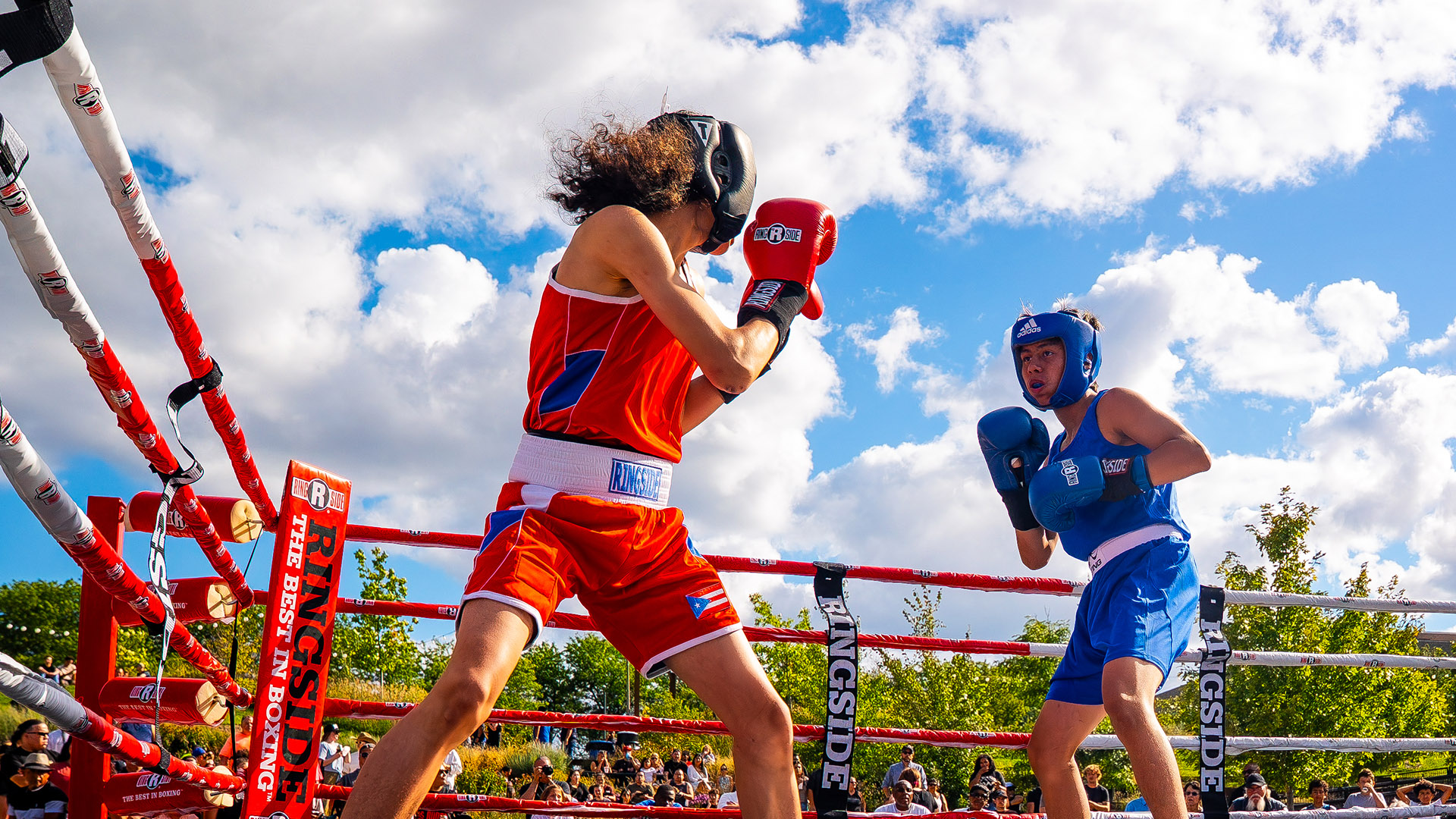 Youth boxers competing in outdoor ring during Harley-Davidson boxing event