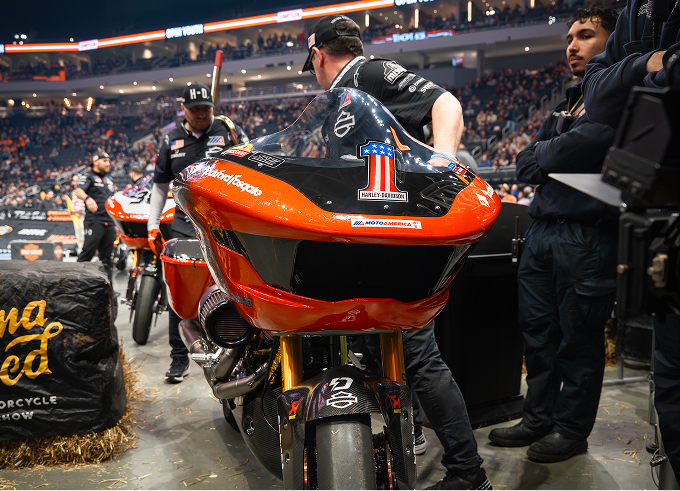 Crew prepares Kyle Wyman’s number 1 racing motorcycle in the pit area as spectators fill the arena