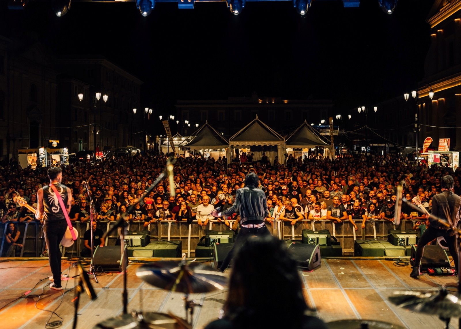 A band performing on stage at an event, with a large crowd enjoying the music.